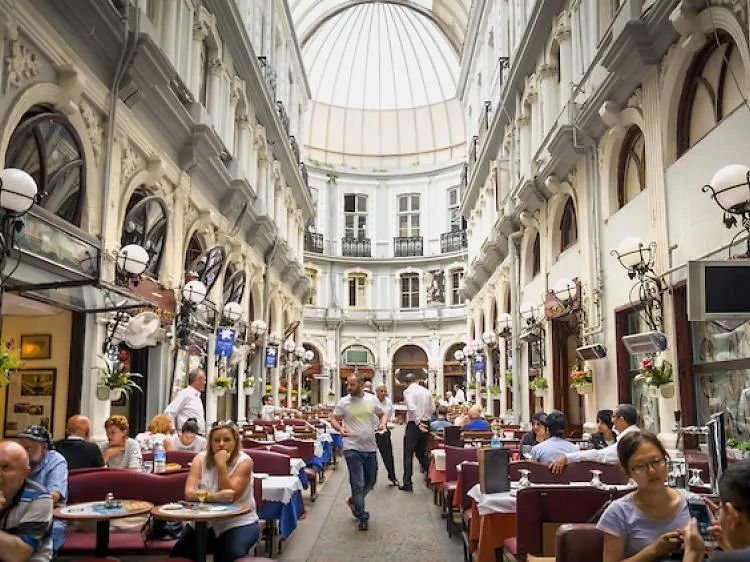 Interior display of Çiçek Pasaj? Istanbul with  people sitting and others walking on the center walkway 