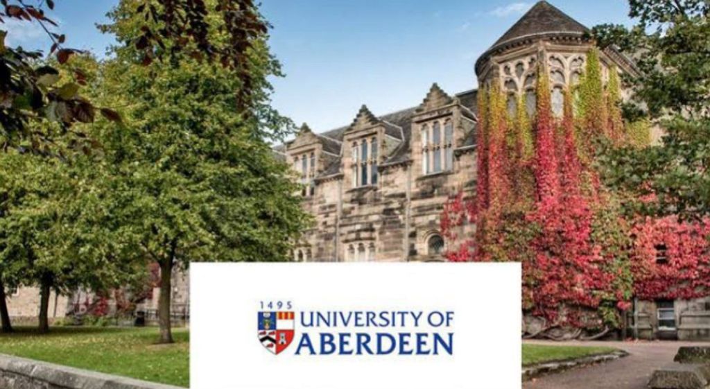 University of Aberdeen UK campus adorned with beautiful flowers of green colors. The logo of the school of displayed on a white background with " University of Aberdeen" written on it 